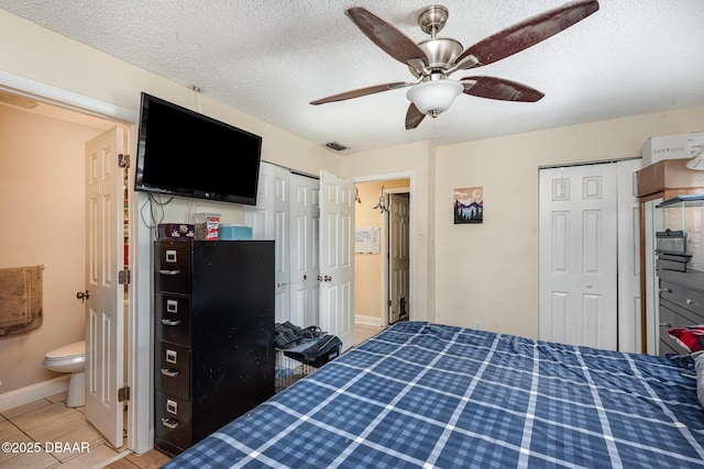 bedroom with ceiling fan, a textured ceiling, baseboards, light tile patterned floors, and visible vents