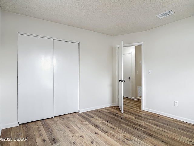 244 Oakleigh Dr, Deland, FL 32724 - unfurnished bedroom featuring wood finished floors, a closet, a textured ceiling, and baseboards