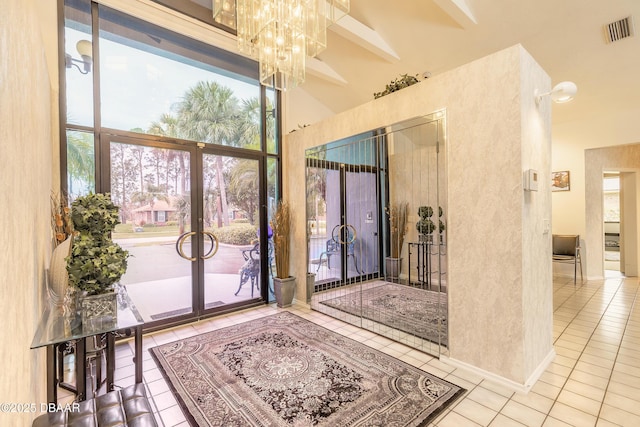 doorway to outside featuring visible vents, a high ceiling, an inviting chandelier, and tile patterned flooring