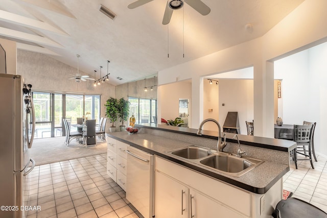 kitchen featuring visible vents, lofted ceiling, freestanding refrigerator, a sink, and dark countertops