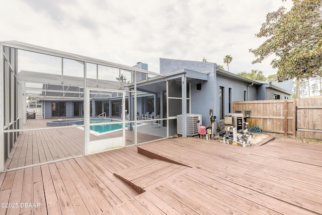 deck with a lanai, fence, central AC unit, and an outdoor pool