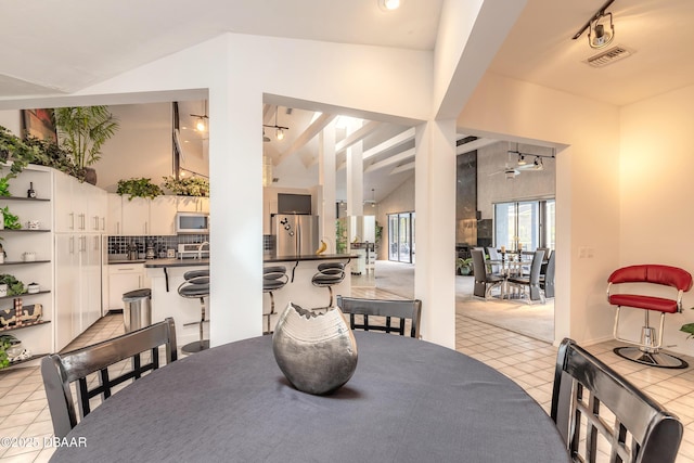 dining room featuring light tile patterned flooring, visible vents, rail lighting, and high vaulted ceiling