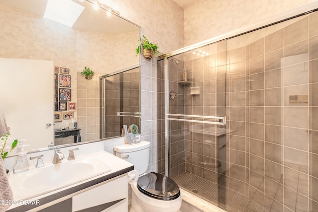 full bath featuring a skylight, toilet, a stall shower, and vanity