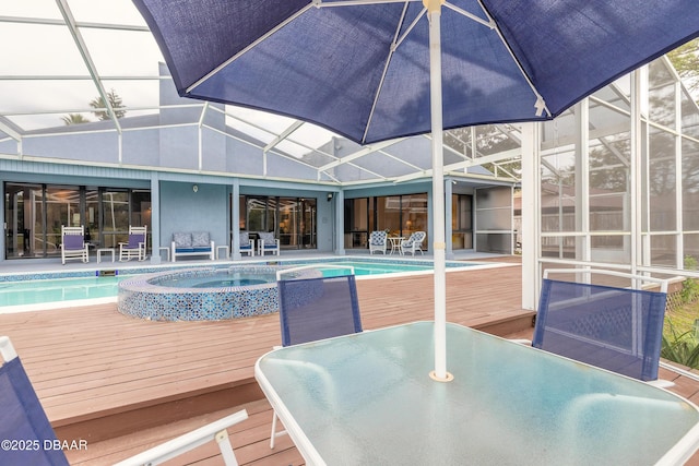 view of pool with outdoor dining area, a deck, glass enclosure, and a pool with connected hot tub