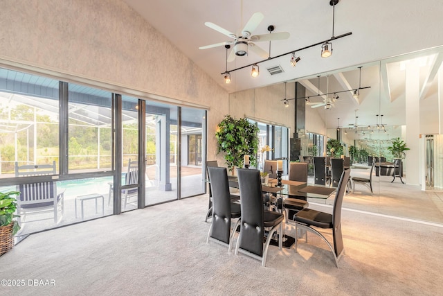 dining space with visible vents, high vaulted ceiling, rail lighting, light colored carpet, and ceiling fan