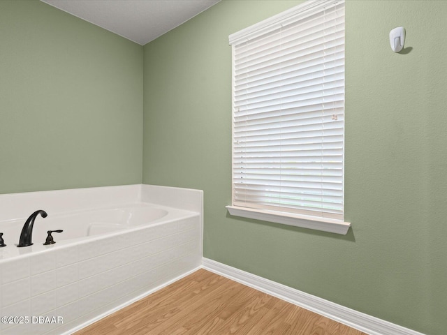 bathroom with a washtub and wood-type flooring