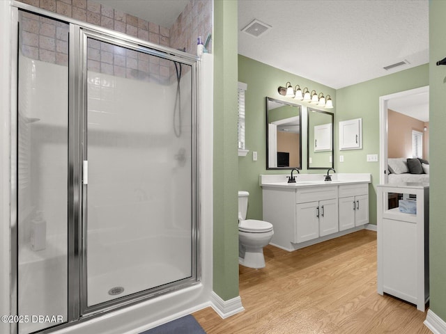 bathroom with wood-type flooring, toilet, an enclosed shower, and vanity