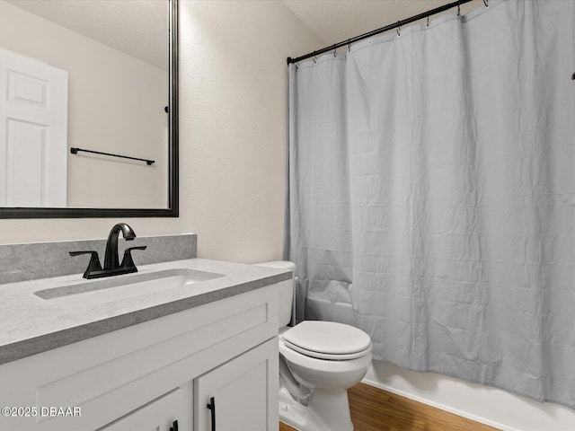 full bathroom featuring toilet, a textured ceiling, vanity, shower / bath combo with shower curtain, and hardwood / wood-style floors