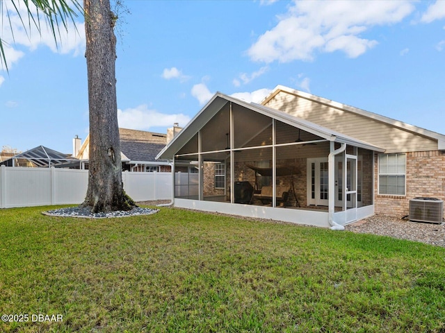 back of house featuring a sunroom, a yard, and central AC