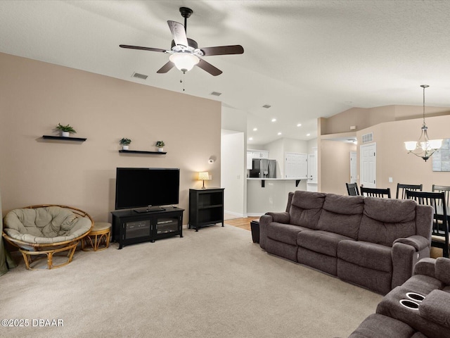 living room featuring ceiling fan with notable chandelier, light colored carpet, and vaulted ceiling