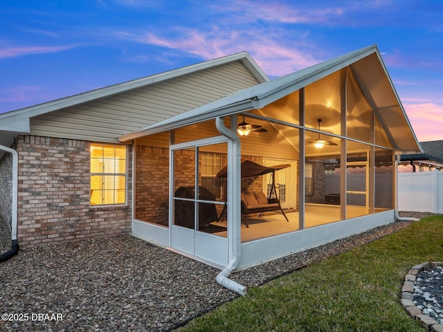 back house at dusk featuring a sunroom