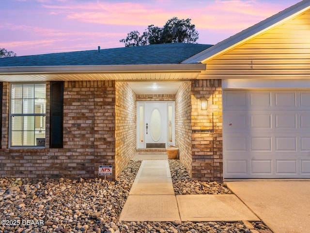 exterior entry at dusk featuring a garage