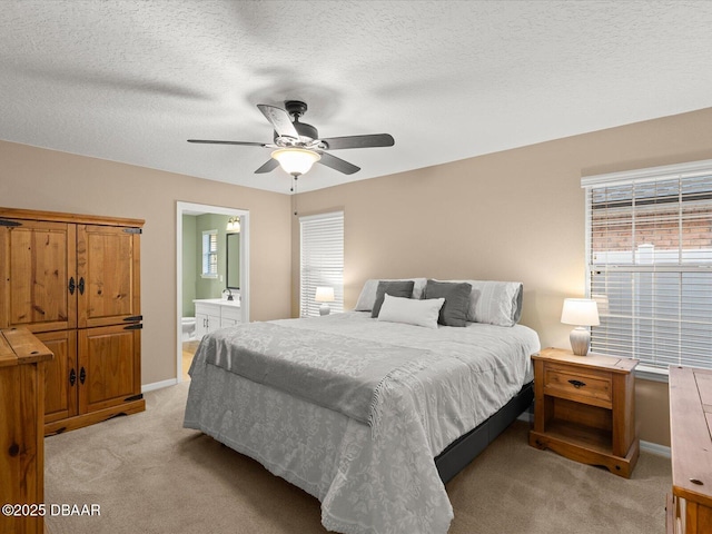 bedroom with ceiling fan, light colored carpet, ensuite bathroom, and a textured ceiling