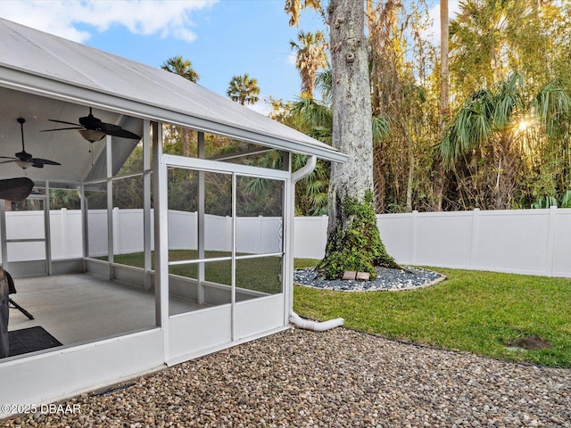 view of yard featuring a sunroom and ceiling fan