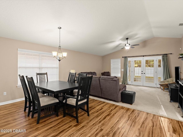 dining area with lofted ceiling, ceiling fan with notable chandelier, light hardwood / wood-style floors, and french doors