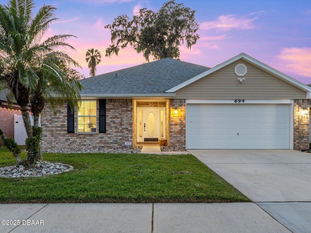 ranch-style house with a garage and a yard