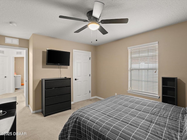 bedroom featuring ceiling fan, light colored carpet, and a textured ceiling