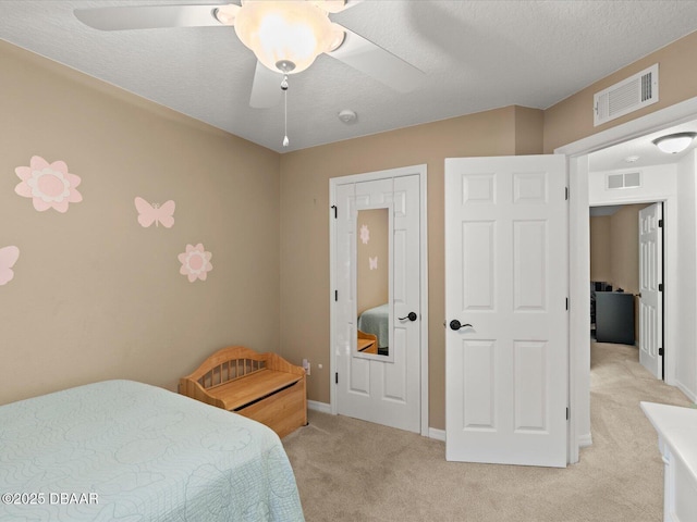 bedroom featuring ceiling fan, light colored carpet, and a textured ceiling