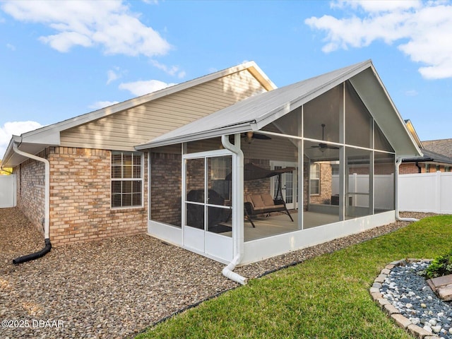 back of house featuring a lawn, a sunroom, and ceiling fan