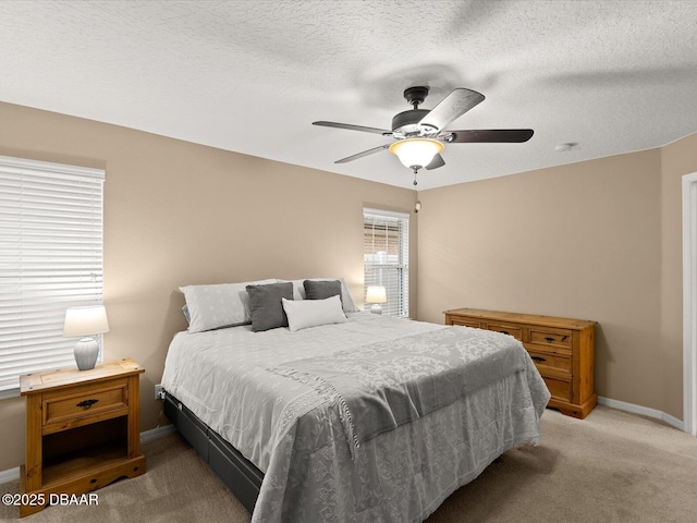 bedroom featuring ceiling fan, light colored carpet, and a textured ceiling