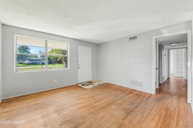 spare room with a textured ceiling and light wood-type flooring