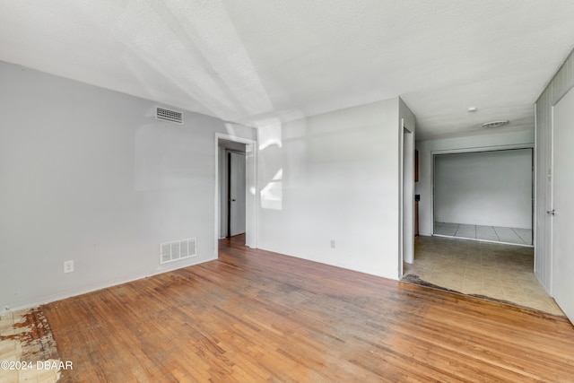 spare room with a textured ceiling and light hardwood / wood-style floors