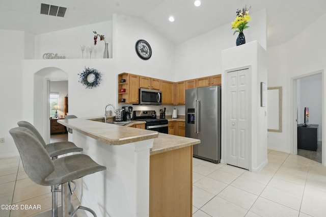 3348 Heath Dr, Deltona, FL 32725 - kitchen featuring stainless steel appliances, high vaulted ceiling, a kitchen bar, light tile patterned floors, and a peninsula