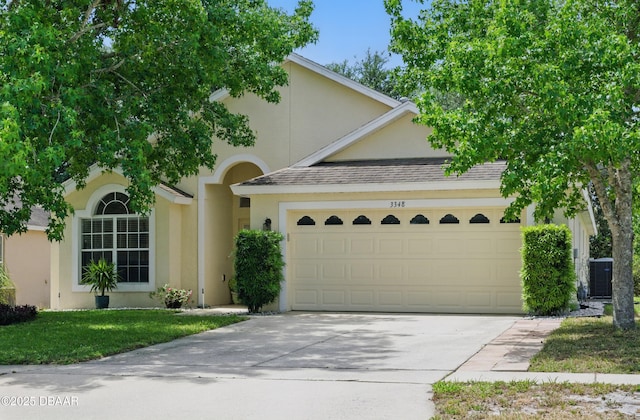 3348 Heath Dr, Deltona, FL 32725 - view of front of house featuring stucco siding, an attached garage, concrete driveway, roof with shingles, and a front yard