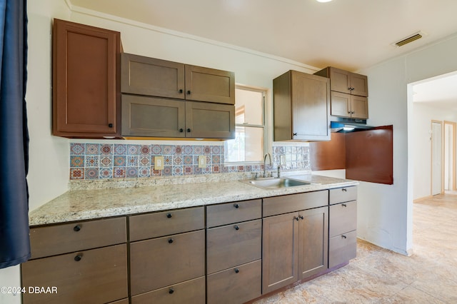 kitchen featuring sink, tasteful backsplash, and light stone countertops