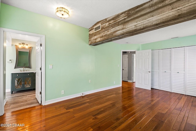 unfurnished bedroom with hardwood / wood-style floors, sink, a textured ceiling, and connected bathroom