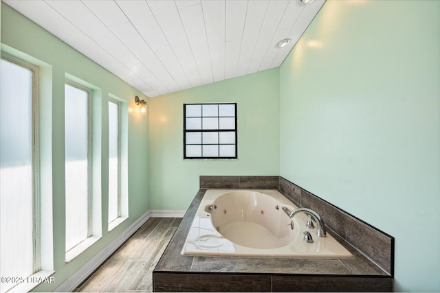 bathroom with a relaxing tiled tub and lofted ceiling