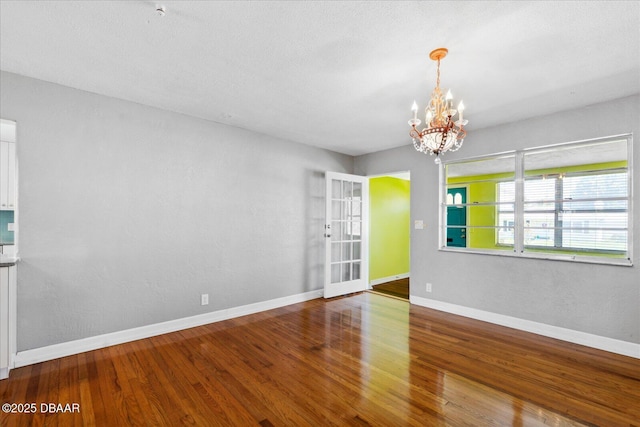 unfurnished room with wood-type flooring and an inviting chandelier