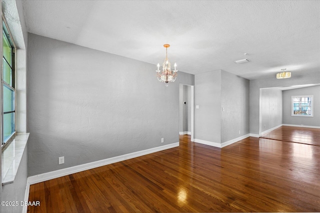 spare room featuring hardwood / wood-style floors, a textured ceiling, and a notable chandelier