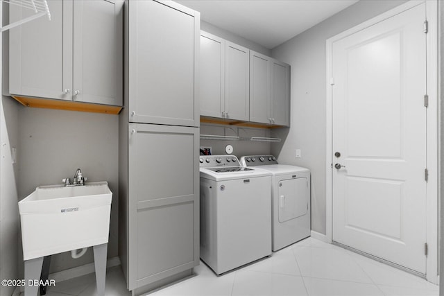 laundry area with independent washer and dryer, cabinets, light tile patterned flooring, and sink