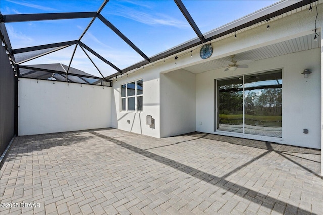 view of patio featuring ceiling fan and glass enclosure