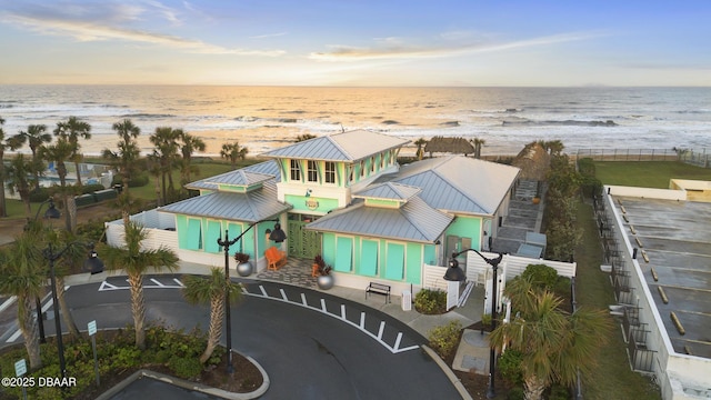 aerial view at dusk with a water view and a view of the beach