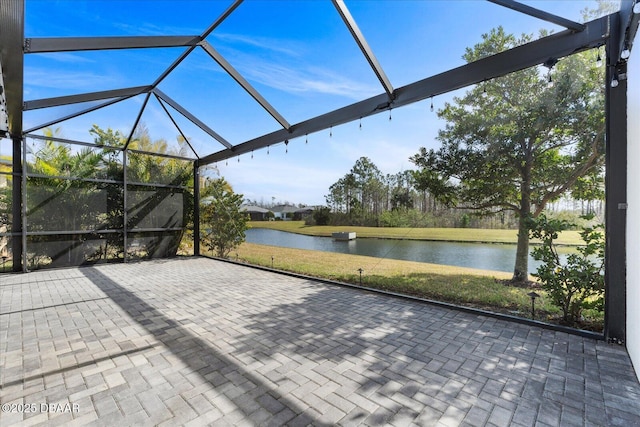 view of patio with a lanai and a water view