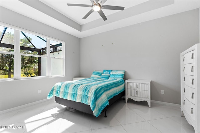 tiled bedroom with ceiling fan and a raised ceiling