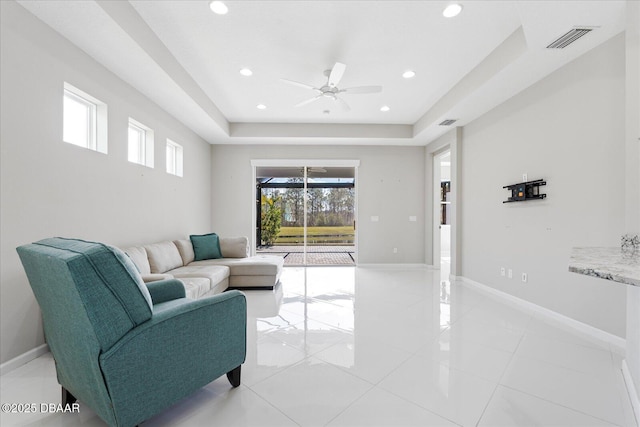 living room with a raised ceiling and ceiling fan