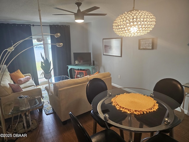 dining room featuring dark wood-type flooring, ceiling fan with notable chandelier, and a textured ceiling