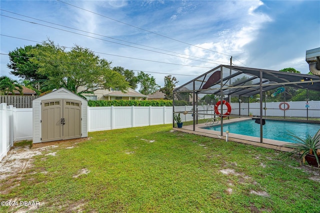 view of yard featuring a fenced in pool, glass enclosure, and a storage unit