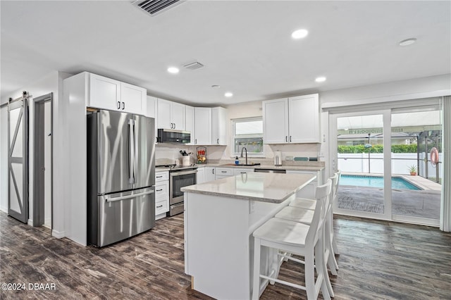 kitchen featuring white cabinets, a kitchen island, a barn door, and stainless steel appliances