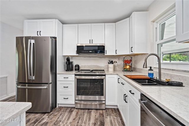 kitchen with stainless steel appliances, white cabinetry, dark wood-type flooring, and sink