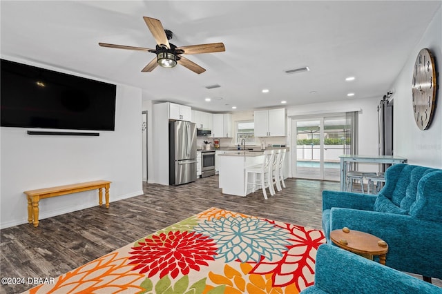 living room featuring ceiling fan, sink, and dark wood-type flooring