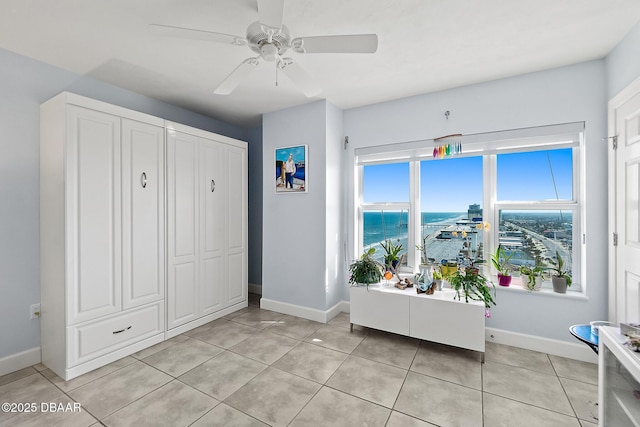 tiled entryway with ceiling fan and a water view