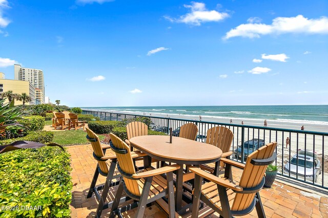 balcony with a water view, a view of the beach, and a patio