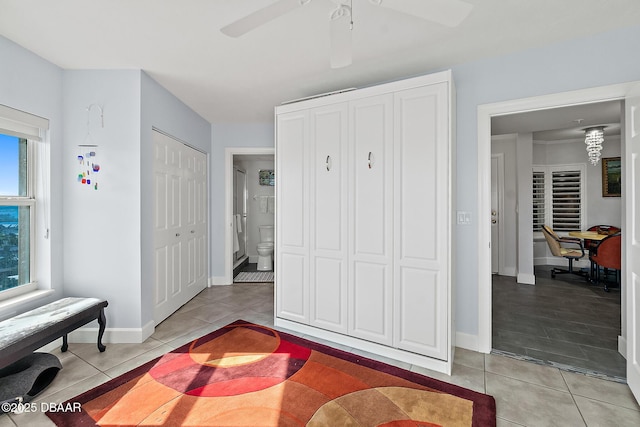 tiled bedroom with ceiling fan, ensuite bathroom, and two closets