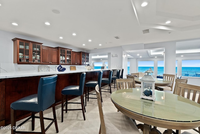 dining area featuring light tile patterned floors and a water view