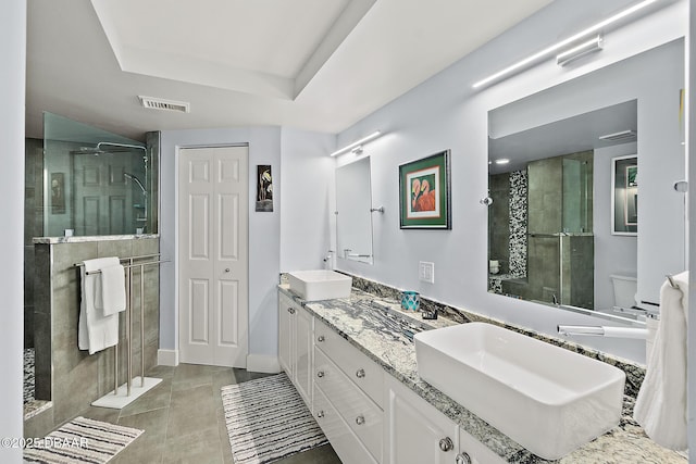 bathroom with vanity, a tray ceiling, tiled shower, and toilet