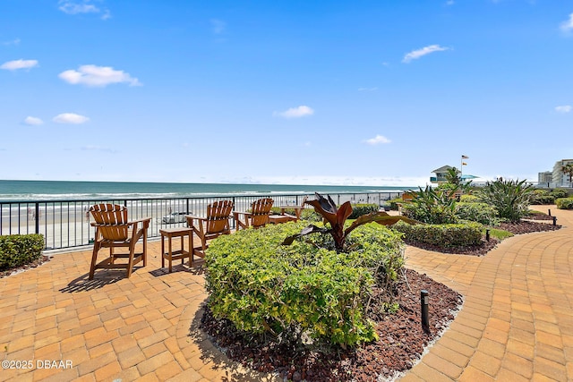 view of patio with a water view and a beach view